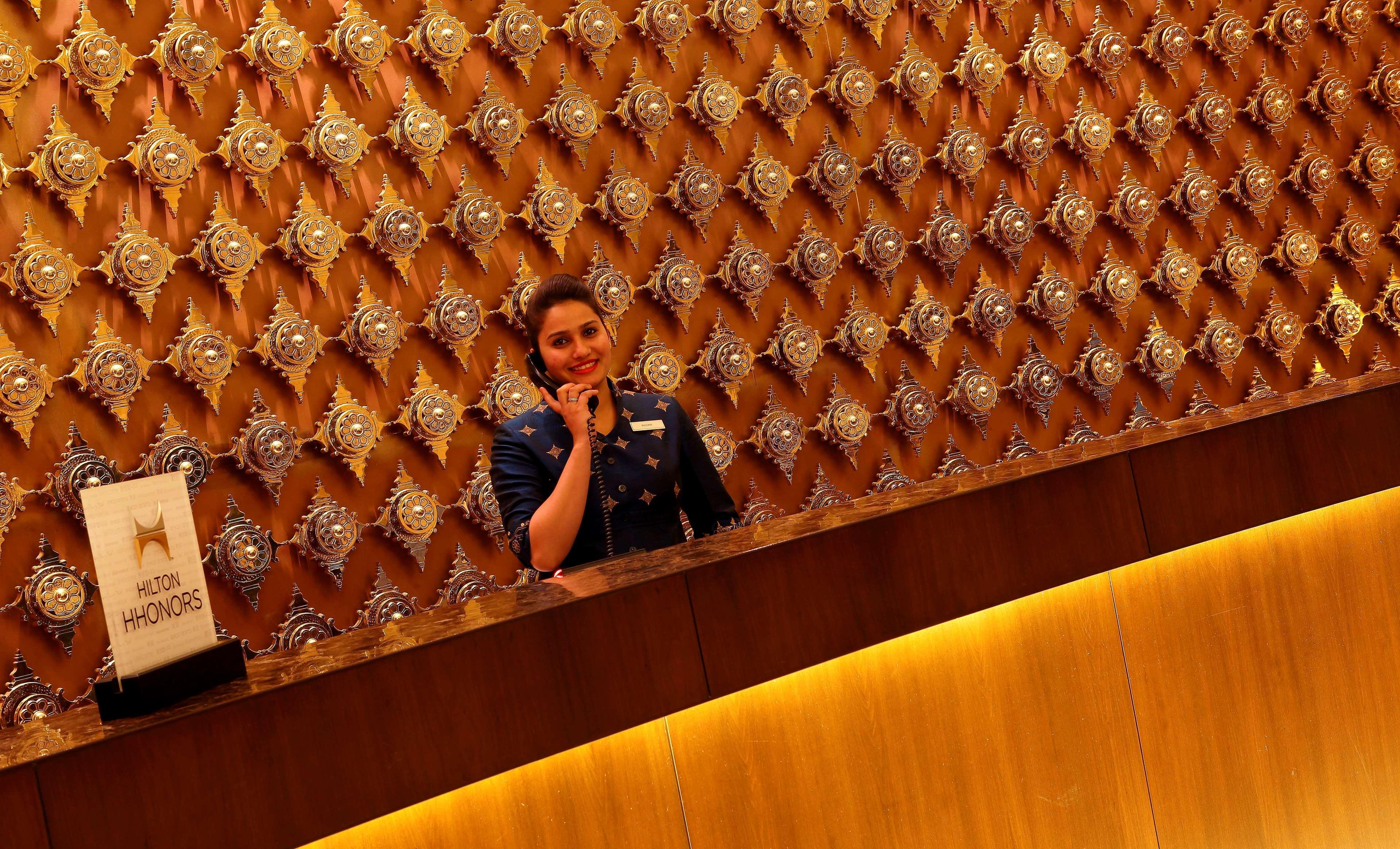 Hilton Jaipur Hotel Kültér fotó A hotel receptionist at work